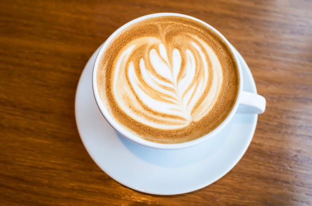 Latte cup with a pattern on a wooden table in a coffee shop