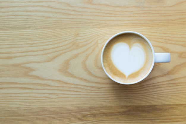 Latte koffiekopje op houten tafel met hartvormige oppervlak