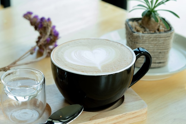 Latte-kunstkoffie in de ochtendtijd met zonlicht op houten lijstachtergrond bij koffiewinkel.