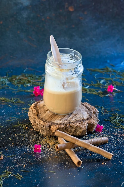 Photo latte macchiato on wooden log with wafers on a christmas background