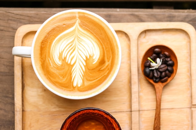 ラテミルククリームの花木製スプーンコーヒー豆の背景