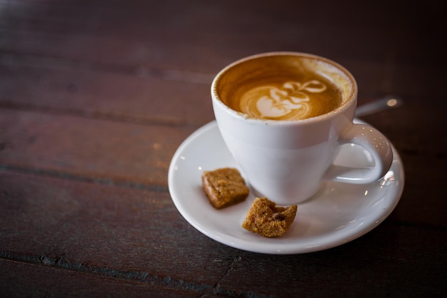 Foto latte warme koffie met melkschuimkunst op een houten tafel