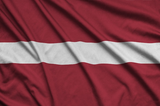 Latvia flag is depicted on a sports cloth fabric with many folds.