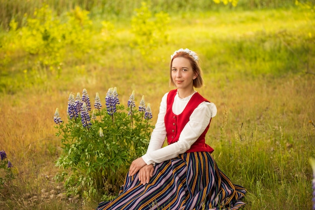 Latvian woman in traditional clothing in field.