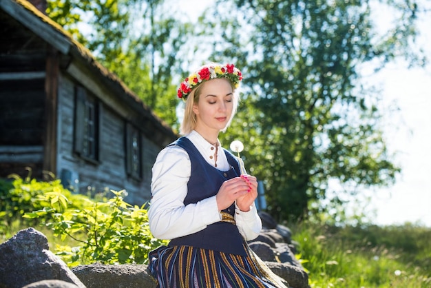 Латышская женщина в традиционной одежде позирует на фоне природы на деревенском фестивале Лиго