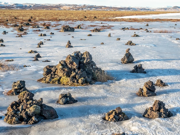 Лавовый хребет Лауфскалавара между рекой, окруженный каменными пирамидами из камней вдоль золотой кольцевой дороги Исландии