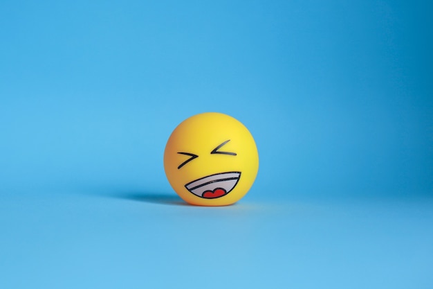 Laugh emoticon isolated on blue background