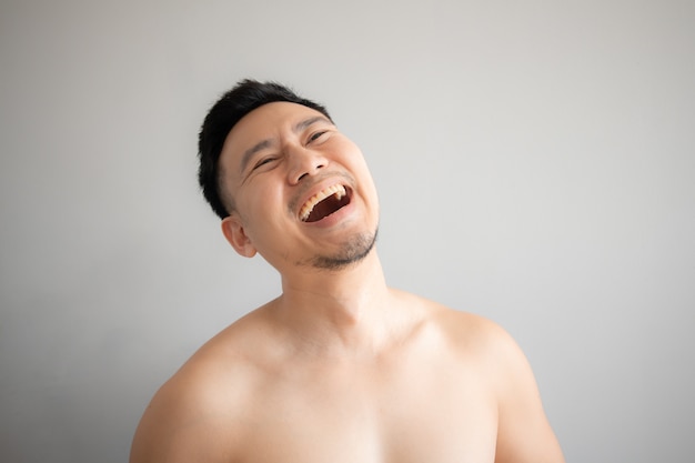 회색 배경에 고립 된 토플리스 초상화에서 아시아 남자의 웃는 얼굴.