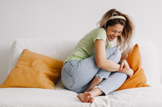 Photo laugh and happy asian woman alone on the sofa good vibes and chill mood