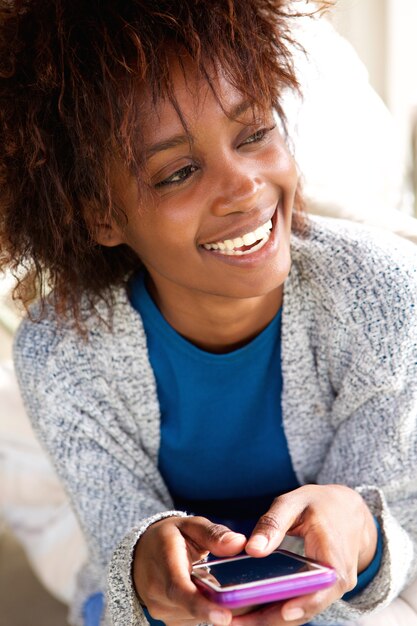 Laughing african woman holding mobile phone