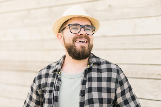 Laughing attractive man wearing hat over wooden background emotion and vacation travel holidays conc