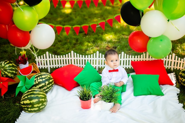 Laughing baby boy 1-2 year old eating watermelon outdoors. Summer party concept