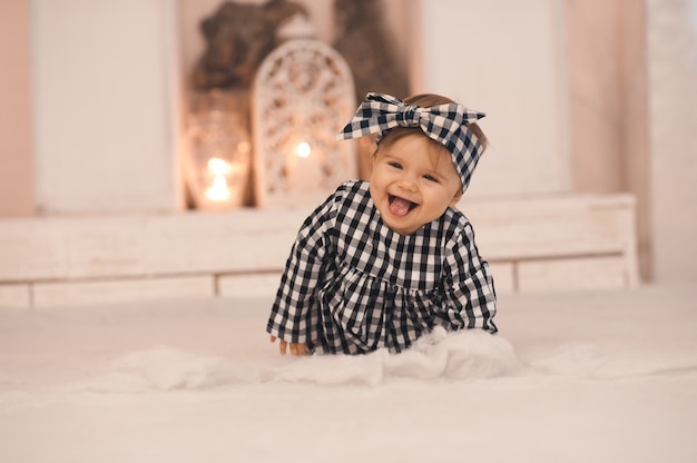 スタイリッシュなヘッドバンドとドレスを着て床を這う笑う女の赤ちゃん