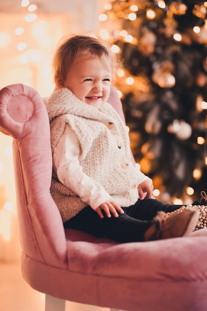 Laughing baby girl under sitting in chair over Christmas lights