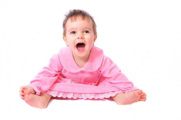 Photo laughing baby in pink dress holding toes