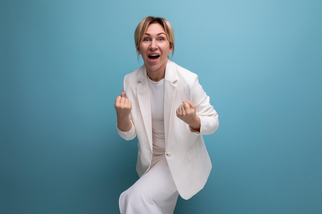 Laughing blonde young european woman dressed in a white jacket and dress on an isolated background