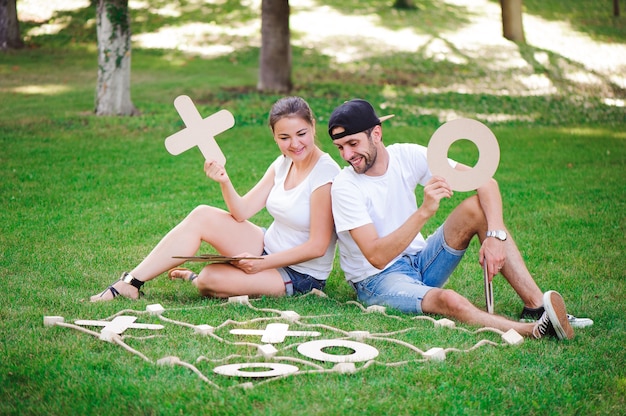 Laughing boy and girl playing tic-tac-toe in the park.