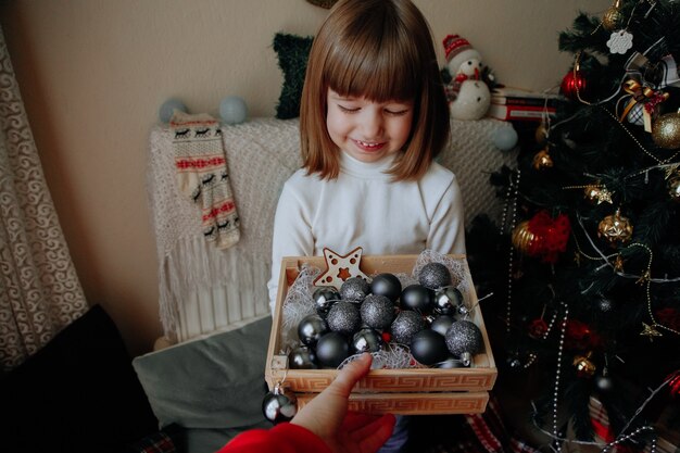 Laughing caucasian girl with decoration box at home with christmas decorations