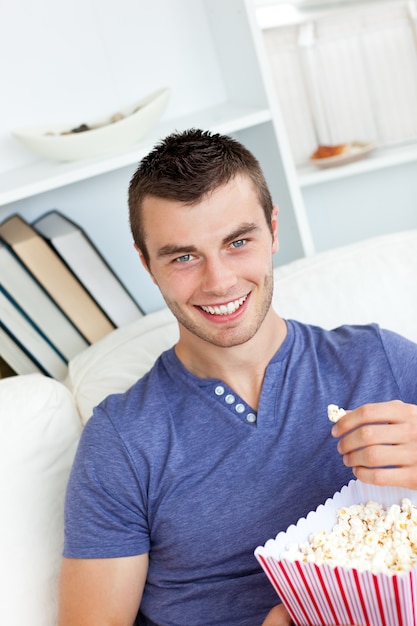 カメラを見てポップコーンを食べる白人の男を笑う