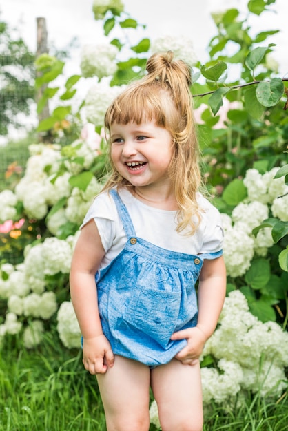 Laughing cheerful baby girl in the village, in rubber boots.