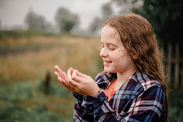 写真 笑っている子供は腕を広げて雨滴をキャッチします