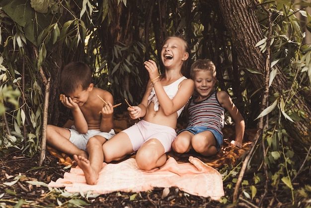 Laughing children play in a hut made of twigs and leaves. Wooden house in the village