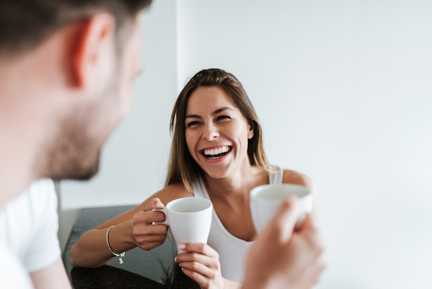 午前中にコーヒーを飲みながら笑っているカップル。