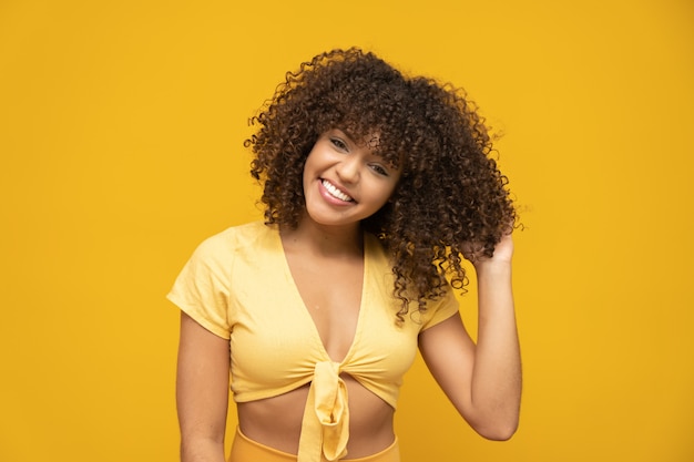 Laughing curly woman in sweater touching her hair