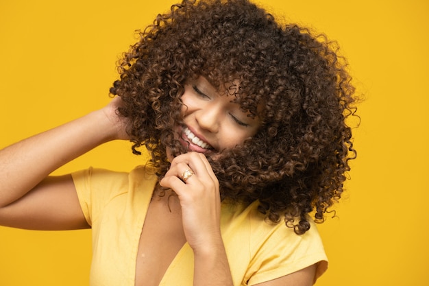 Laughing curly woman in sweater touching her hair