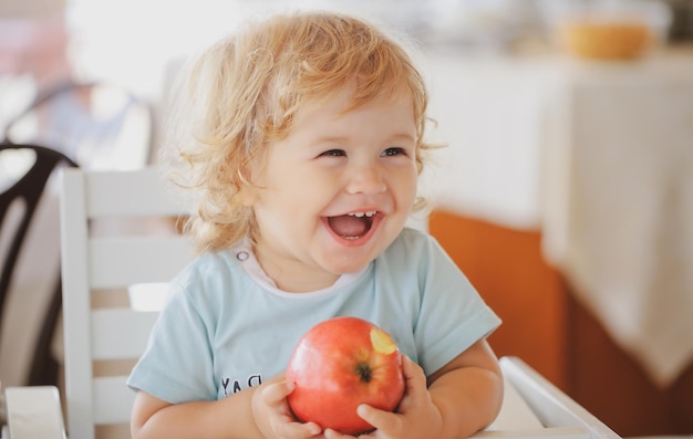 Laughing cute child eating apple Cute baby eat apples Portrait of cute smiling laughing Caucasian ch...