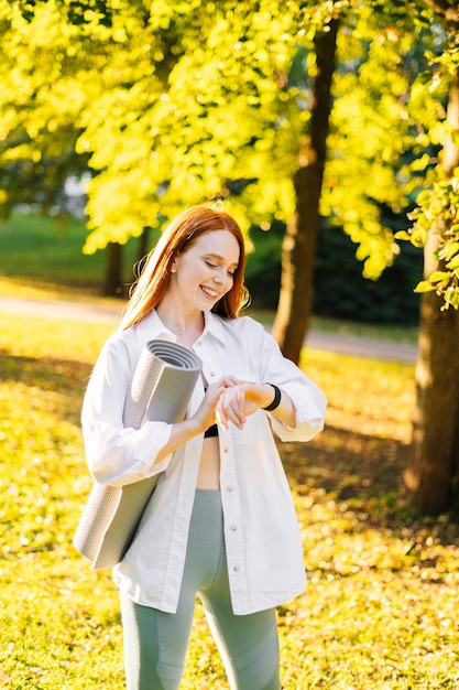 Laughing cute redhaired young woman looking at sports smart watch