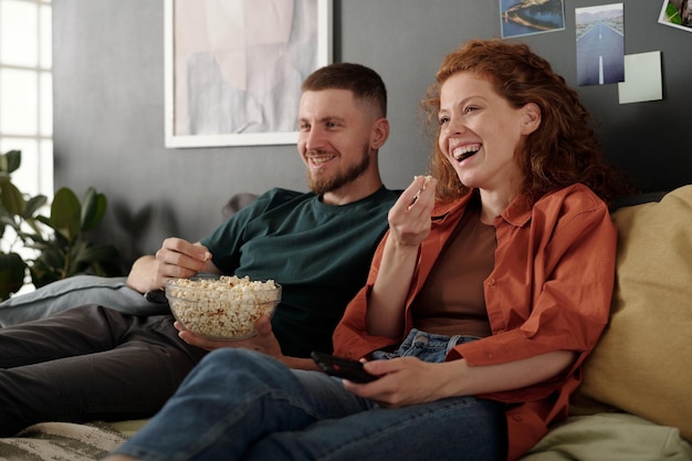 laughing and eating popcorn from bowl