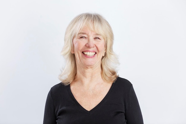 Photo laughing elderly woman beautiful lady in a black sweater positive and optimistic white background closeup