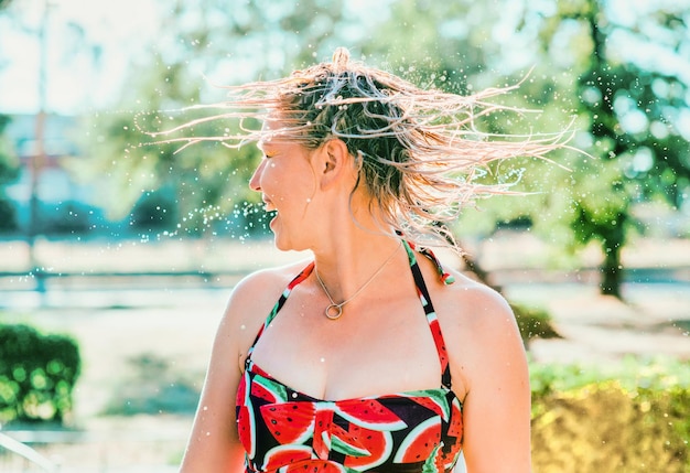 laughing emotional blonde woman with wet hair making water splashes. Holidays, happiness, fun