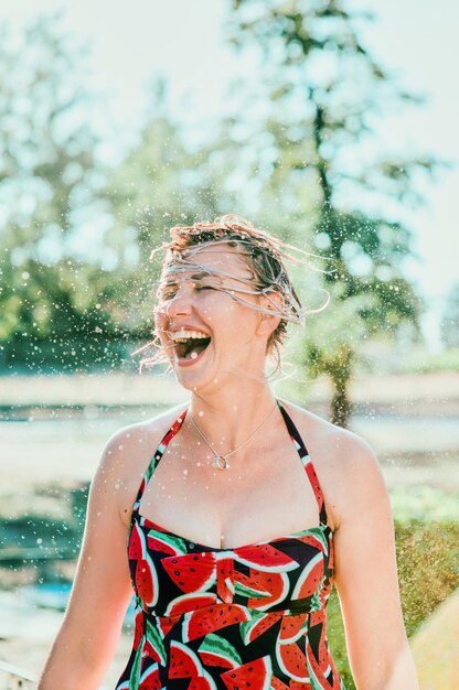 laughing emotional blonde woman with wet hair making water splashes. Holidays, happiness, fun