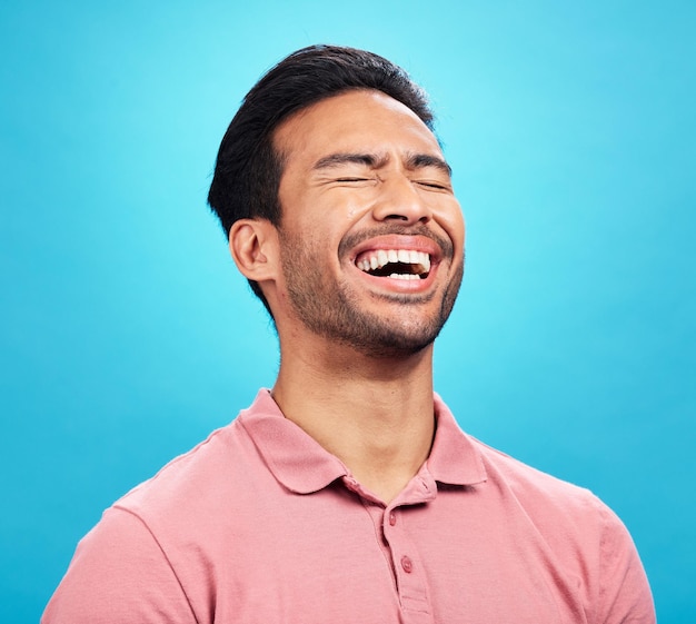 Laughing funny comedy and man in studio isolated on a blue background Comic humor and male person laugh at joke laughter and happiness cheerful and carefree for hilarious smile excited or emoji