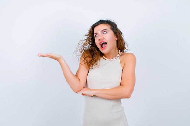 Laughing girl is looking and pointing left with hand on white background