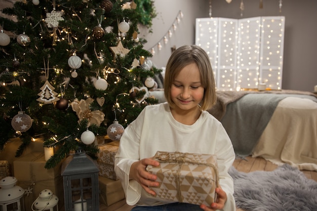 Laughing girl with a gift at the Christmas tree, soft focus