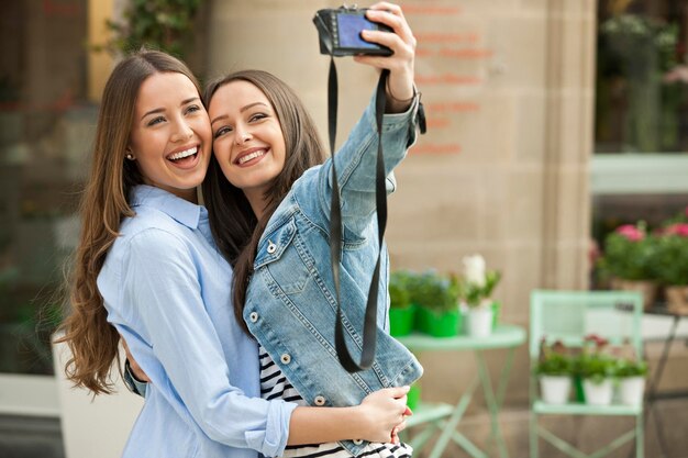 Laughing girlfriends taking a selfie in the street