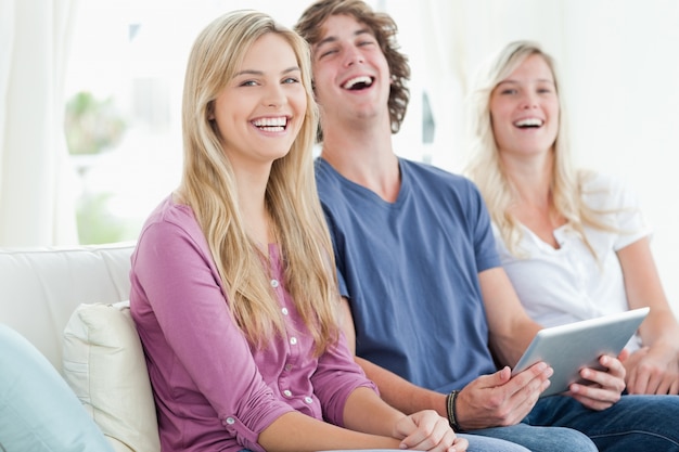 Laughing group of friends sitting as they use a tablet