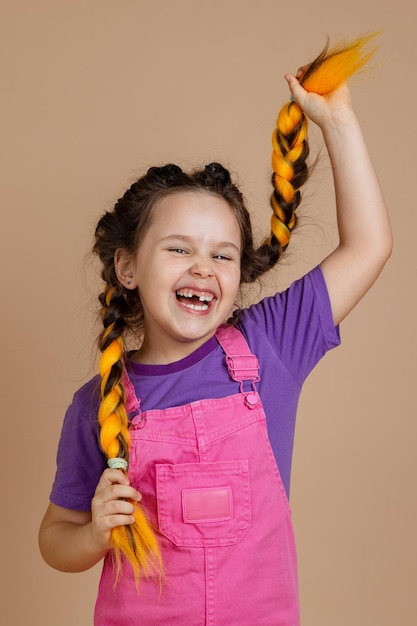 Laughing happy young girl with yellow kanekalon braids with opened mouth with missing tooth holding