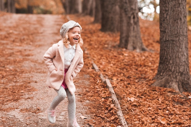 Laughing kid girl wearing winter jacket and knitted hat in park