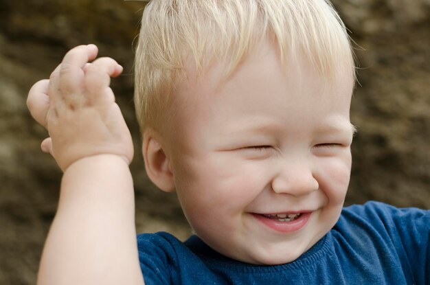 A laughing little boy toddler is a blonde closeup portrait outdoors Happiness emotion