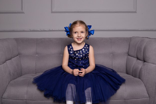 Laughing little cute child girl in blue dress and with pigtails