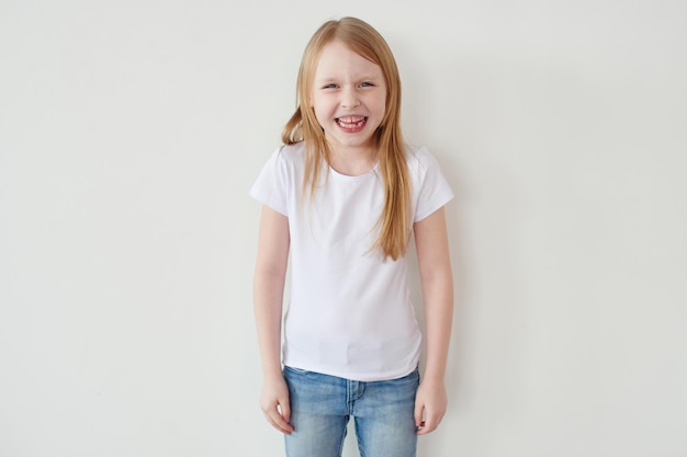 Laughing little girl the blonde on a white background