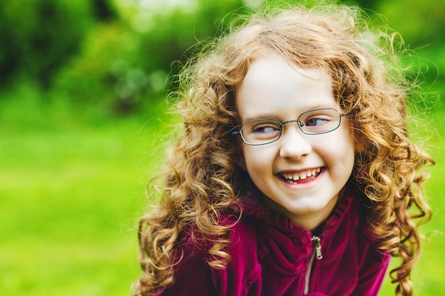 Laughing little girl in eyeglasses in spring park.