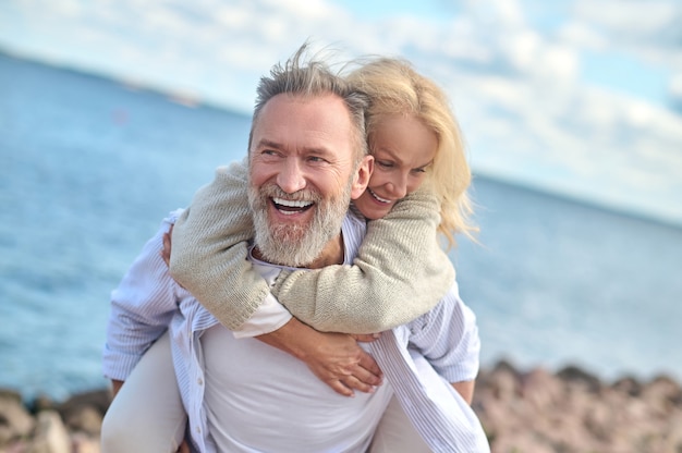 Laughing man carrying woman on his back