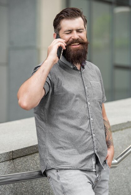 laughing man speak on smartphone outside man speak on smartphone in the street photo of man speak on smartphone man speak on smartphone outdoor