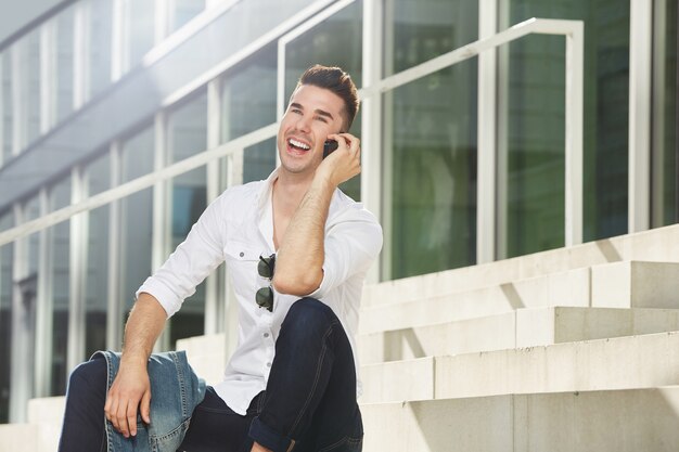 Laughing man on telephone all sitting outside in city