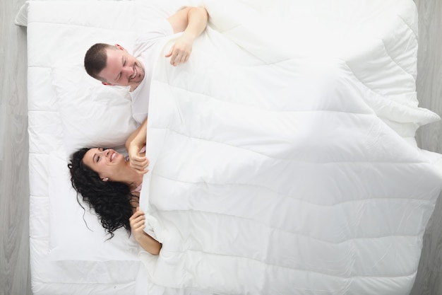 Laughing man and woman on large white bed